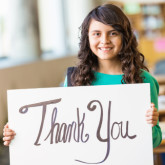 A young Hispanic girl holds up a sign saying "Thank You"