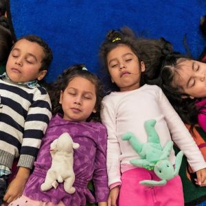 Kids lying on floor with stuffed animals on their tummys